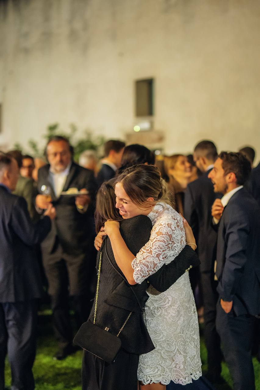 Due donne che si abbracciano durante un evento serale all’aperto in La mia famiglia lavorativa