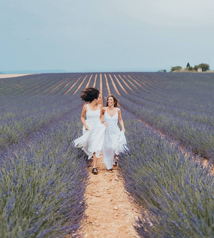 Due donne in abiti bianchi corrono tra i campi di lavanda su La mia famiglia lavorativa