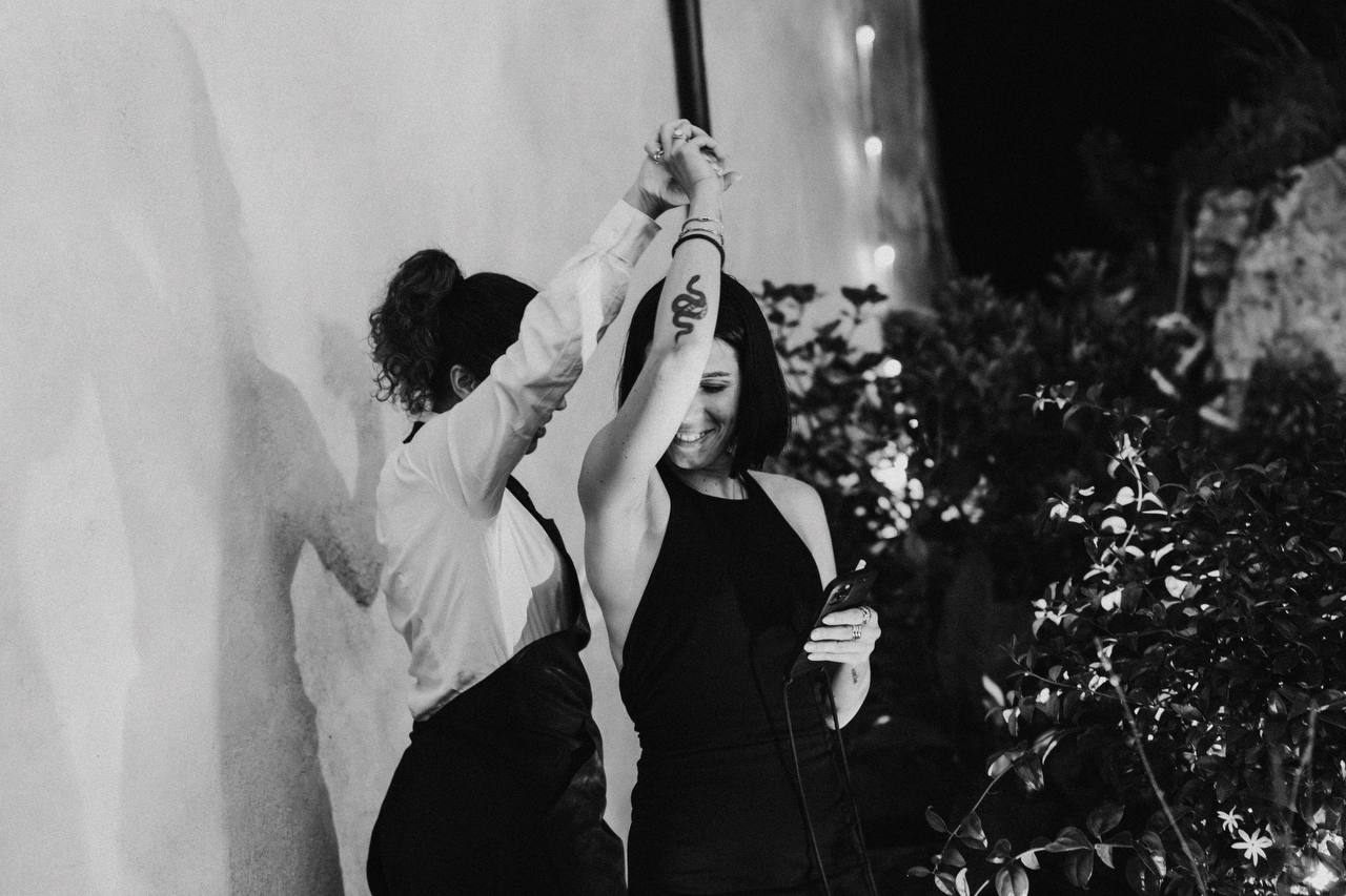 Due donne che ballano tenendosi per mano, una con tatuaggio di serpente sul braccio